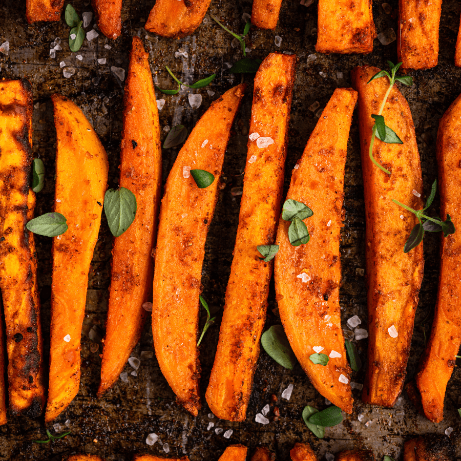 Slices of sweet potatoes on a baking sheet, seasoned with spices